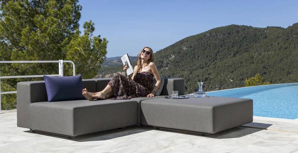 Woman sitting on balcony on outdoor lounge sofa
